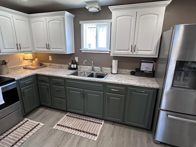 kitchen featuring white cabinets, light wood-type flooring, appliances with stainless steel finishes, and sink