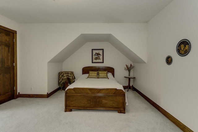 bedroom with vaulted ceiling, baseboards, and light carpet