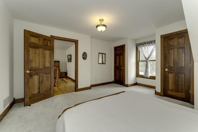 bedroom featuring visible vents, baseboards, and light colored carpet