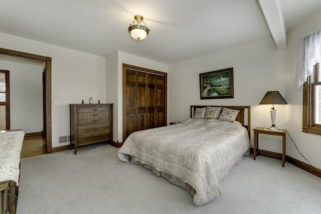 carpeted bedroom with beam ceiling and a closet