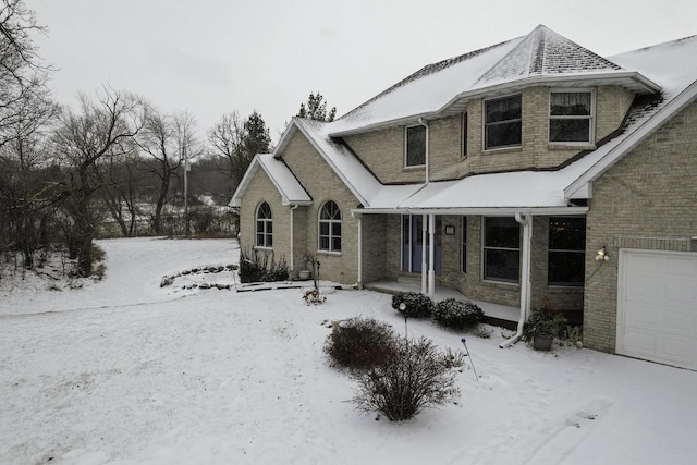 traditional home featuring a garage, covered porch, and brick siding