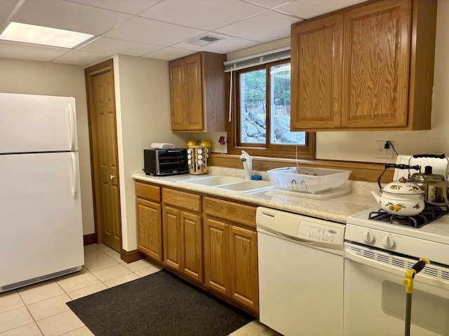 kitchen with visible vents, a sink, a drop ceiling, white appliances, and light countertops