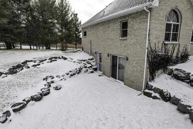 view of snowy exterior with brick siding