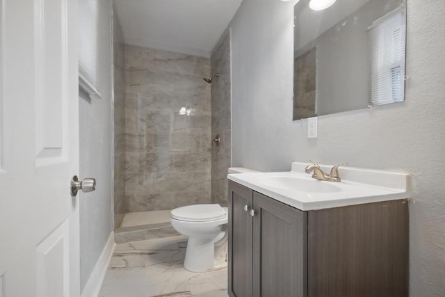 bathroom with tiled shower, vanity, and toilet