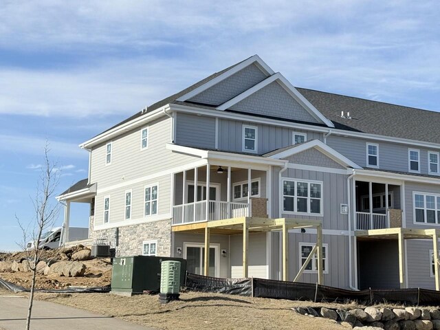 back of property featuring stone siding, board and batten siding, and cooling unit