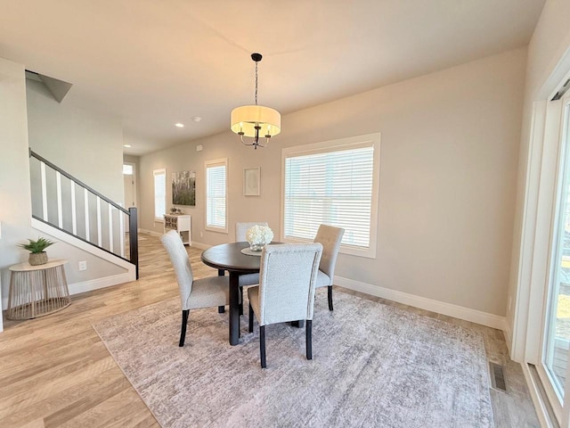 dining area featuring stairway, baseboards, visible vents, and wood finished floors