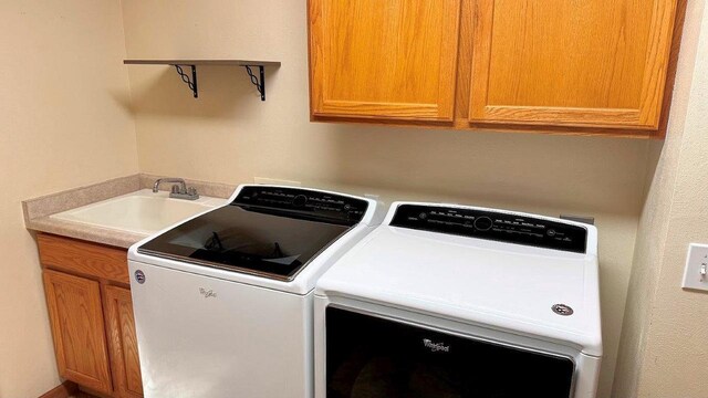 washroom with cabinets, sink, and washing machine and dryer