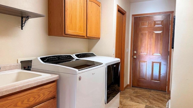 clothes washing area with sink, independent washer and dryer, and cabinets