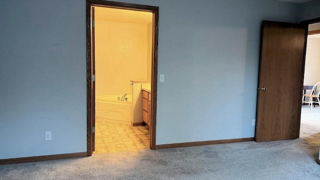 unfurnished bedroom with connected bathroom and light colored carpet