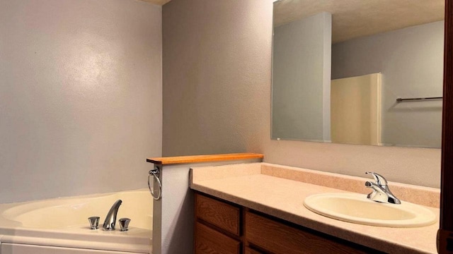 bathroom featuring vanity, a washtub, and a textured ceiling