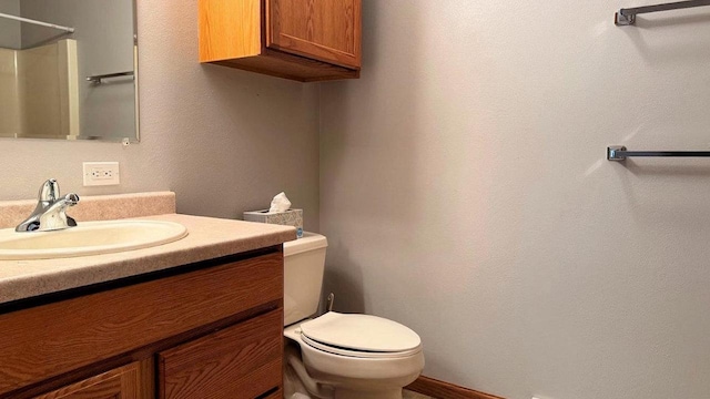 bathroom with toilet, a shower, and vanity