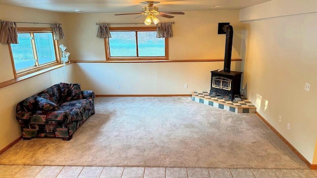 unfurnished room featuring ceiling fan, a wood stove, and carpet flooring