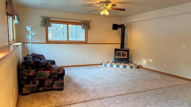 unfurnished living room featuring light carpet, ceiling fan, and a wood stove