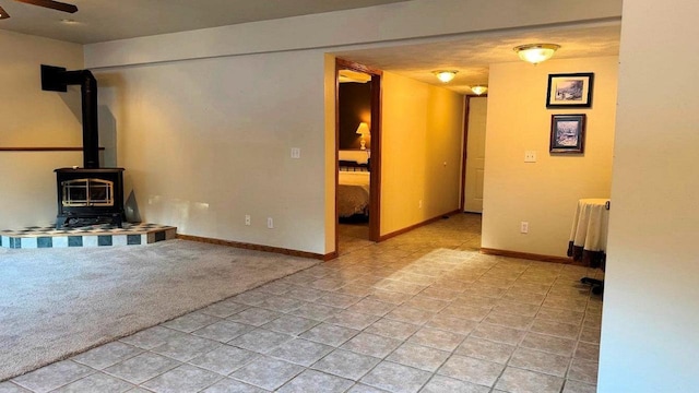 unfurnished living room featuring ceiling fan, radiator, and a wood stove