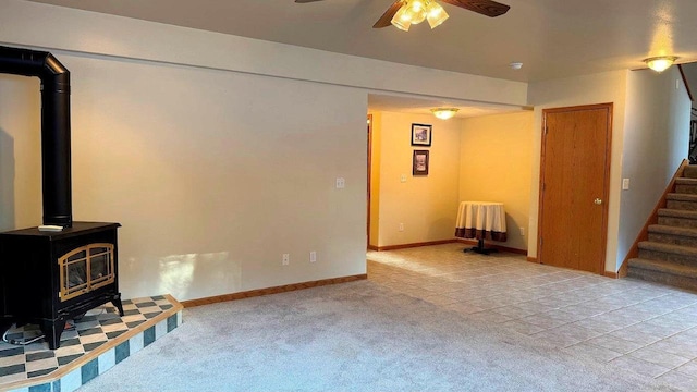 living room featuring ceiling fan, light colored carpet, and a wood stove