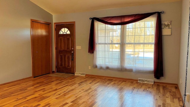 foyer entrance with light hardwood / wood-style floors, plenty of natural light, and lofted ceiling