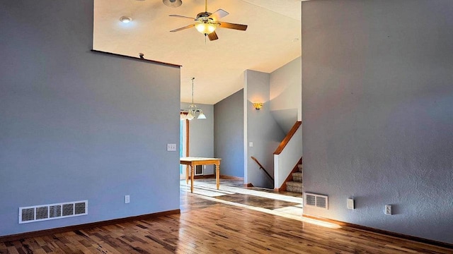 empty room featuring ceiling fan with notable chandelier, wood-type flooring, and lofted ceiling