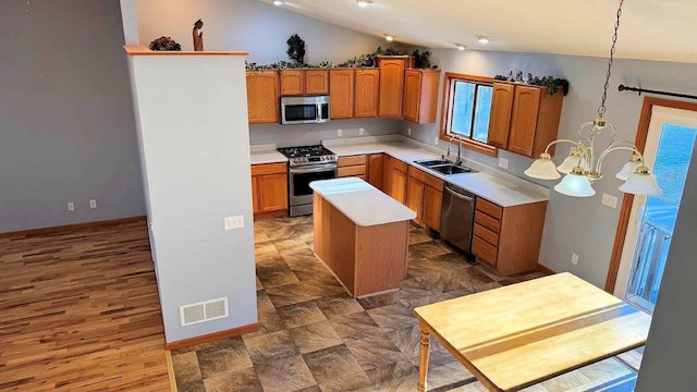 kitchen featuring lofted ceiling, a center island, sink, hanging light fixtures, and appliances with stainless steel finishes