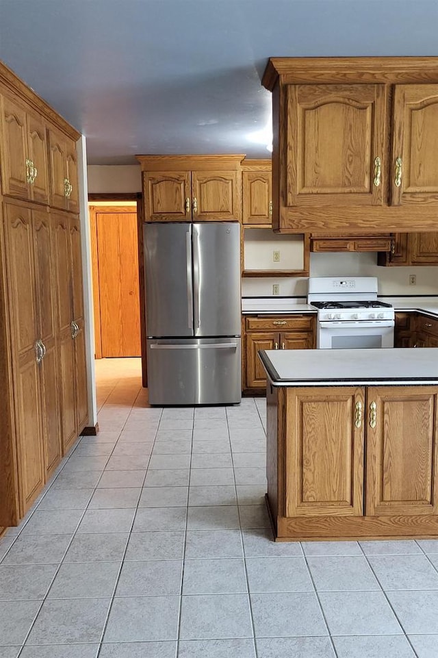 kitchen featuring white gas stove, stainless steel refrigerator, and light tile patterned floors