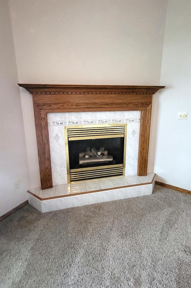 interior details featuring a tiled fireplace and carpet