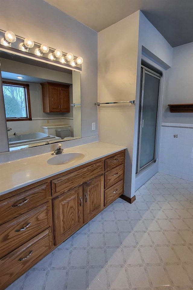 bathroom with vanity, tile walls, and a shower with shower door