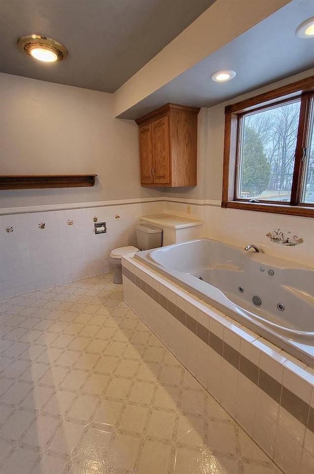 bathroom featuring tiled bath, tile walls, and toilet