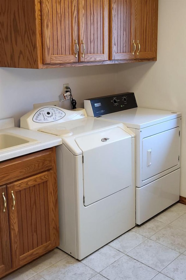 laundry room featuring cabinets, washer and dryer, and light tile patterned floors