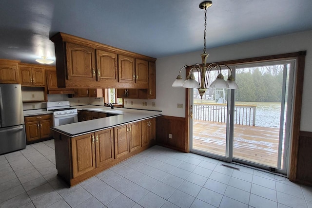 kitchen with sink, stainless steel fridge, gas range gas stove, an inviting chandelier, and hanging light fixtures