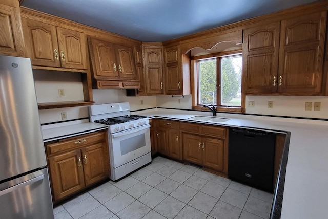 kitchen featuring sink, light tile patterned floors, stainless steel refrigerator, dishwasher, and white range with gas cooktop