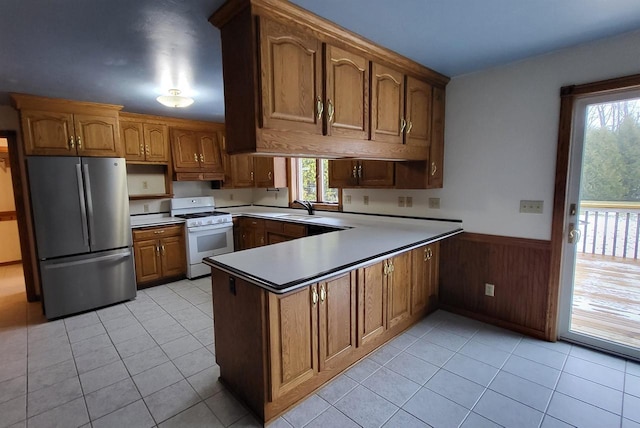 kitchen with stainless steel refrigerator, a healthy amount of sunlight, sink, and white gas range oven