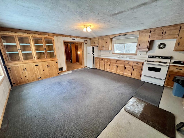 kitchen with sink, white appliances, carpet, and a textured ceiling