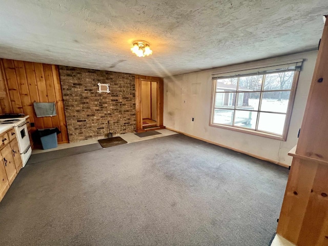 unfurnished living room with a textured ceiling, carpet flooring, and wood walls