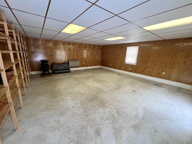 basement featuring a drop ceiling and wooden walls