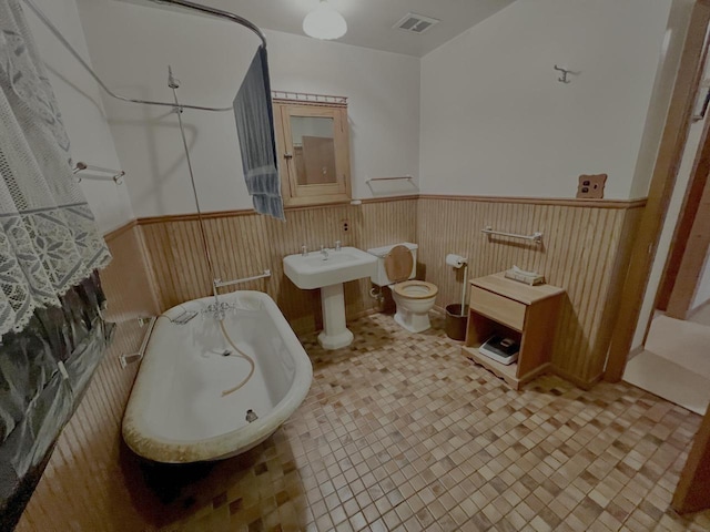 bathroom with toilet, sink, a tub, and tile patterned floors