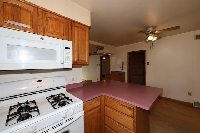 kitchen featuring ceiling fan, white appliances, kitchen peninsula, and dark wood-type flooring