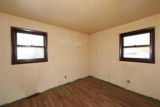 empty room with plenty of natural light and dark hardwood / wood-style flooring