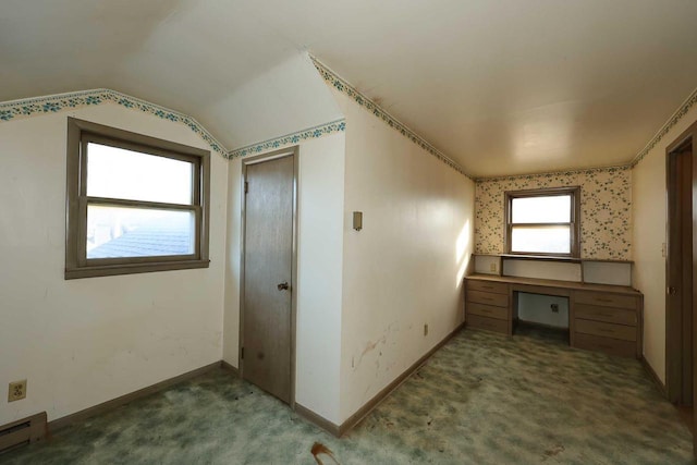 additional living space featuring dark colored carpet, a baseboard radiator, lofted ceiling, and built in desk