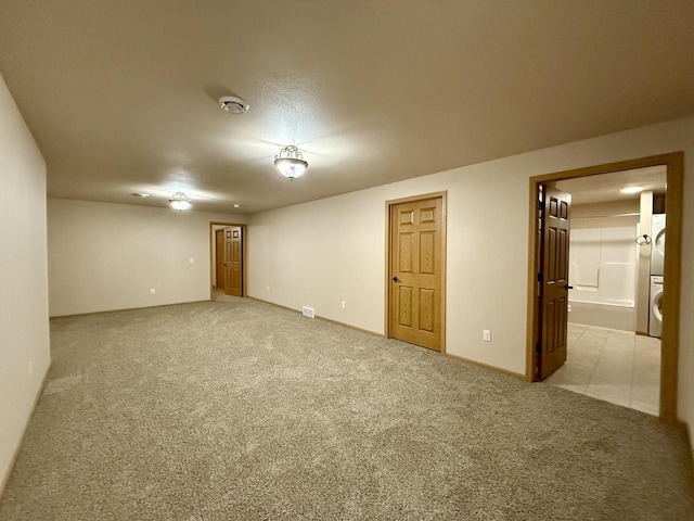 spare room with light carpet and stacked washer and dryer