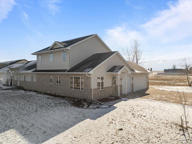 snow covered house featuring a garage