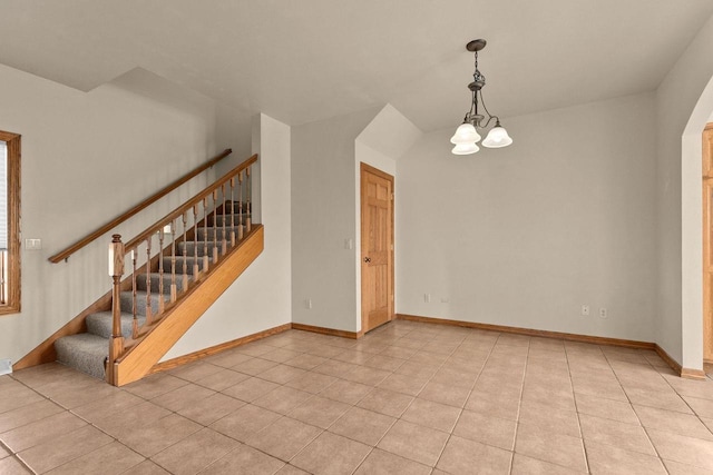 spare room featuring light tile patterned floors and a chandelier