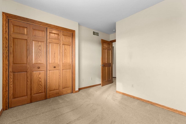 unfurnished bedroom with a closet and light colored carpet