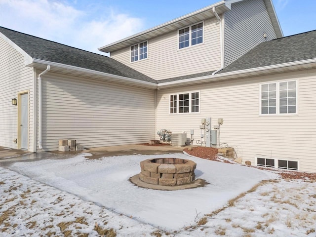 snow covered rear of property with an outdoor fire pit and central AC