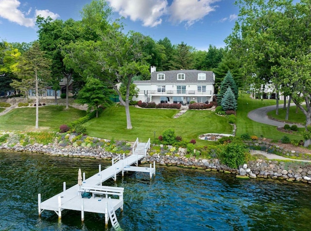 exterior space featuring a water view, a lawn, and a balcony