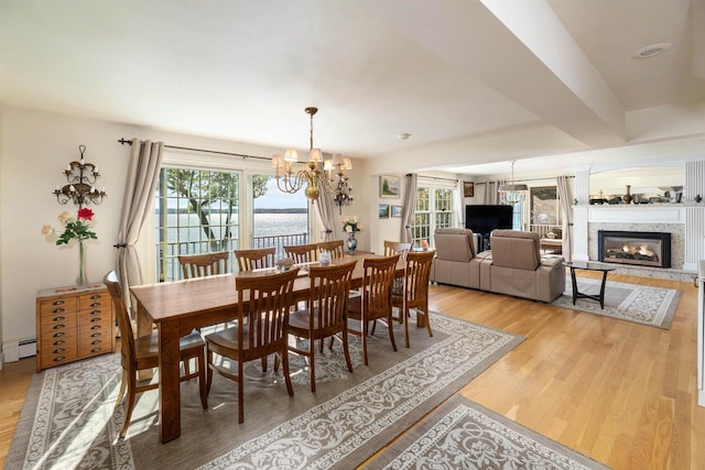 dining space featuring hardwood / wood-style flooring, a baseboard heating unit, and a chandelier