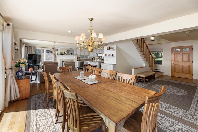 dining space with hardwood / wood-style flooring, baseboard heating, and a chandelier