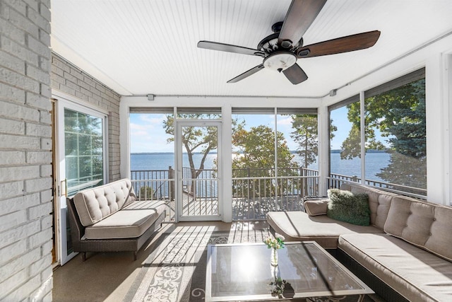 sunroom with ceiling fan, a wealth of natural light, and a water view