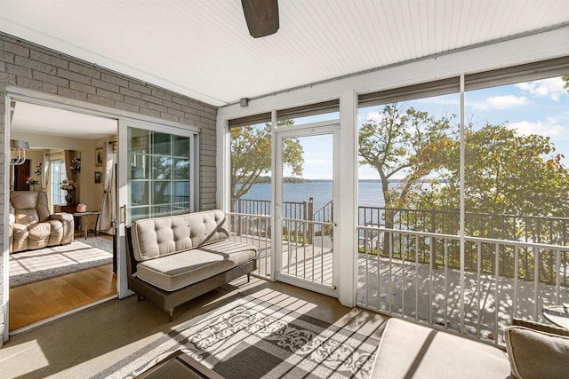 sunroom with a water view and ceiling fan