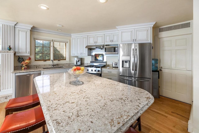 kitchen with light stone counters, a kitchen breakfast bar, sink, and stainless steel appliances