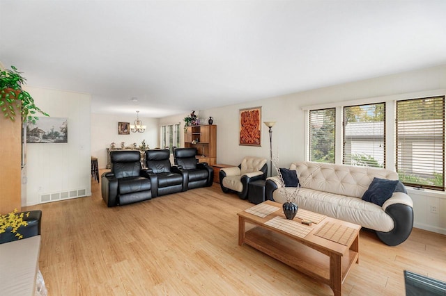 living room with light wood-type flooring, a wealth of natural light, and a chandelier