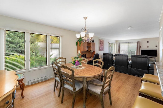 dining space with an inviting chandelier and light hardwood / wood-style flooring